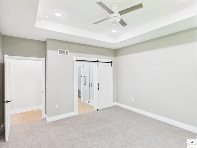 1248 Rich Blvd, Warrensburg, MO 64093 - unfurnished bedroom with light carpet, a raised ceiling, recessed lighting, a barn door, and a ceiling fan
