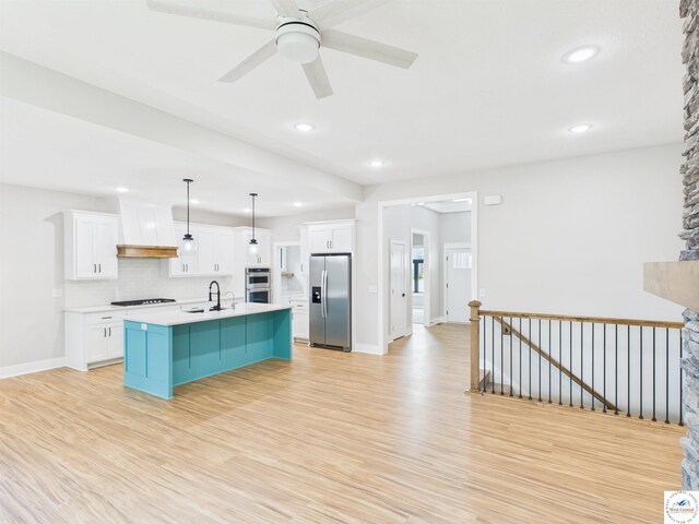 1248 Rich Blvd, Warrensburg, MO 64093 - kitchen featuring appliances with stainless steel finishes, light wood-style floors, white cabinetry, light countertops, and an island with sink