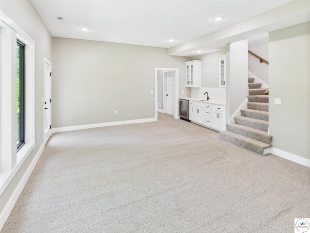 1248 Rich Blvd, Warrensburg, MO 64093 - unfurnished living room with beverage cooler, light carpet, stairway, and recessed lighting