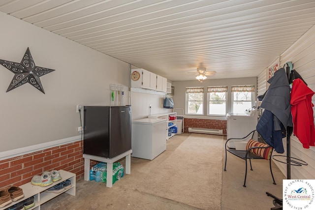 kitchen featuring refrigerator, light colored carpet, brick wall, baseboard heating, and white cabinetry