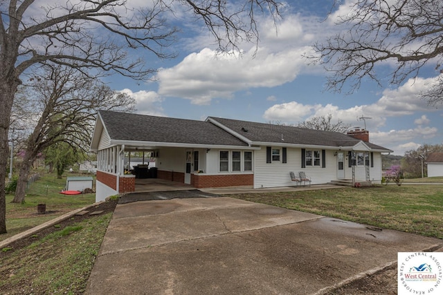 single story home with a front yard, an attached carport, a chimney, brick siding, and concrete driveway