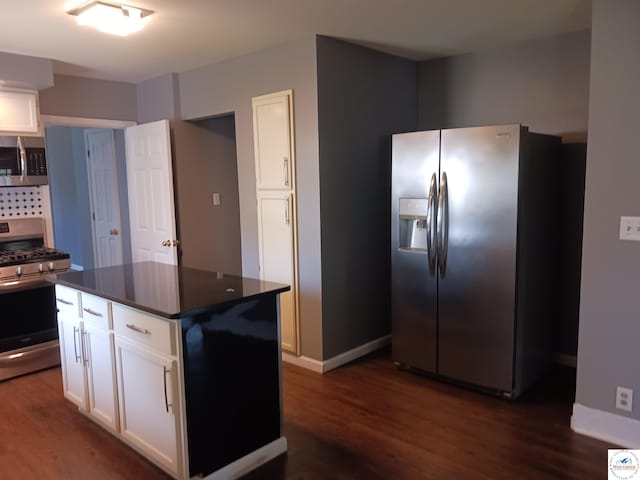 501 S Oak St, Versailles, MO 65084 - kitchen featuring appliances with stainless steel finishes, dark countertops, dark wood-style floors, and white cabinets