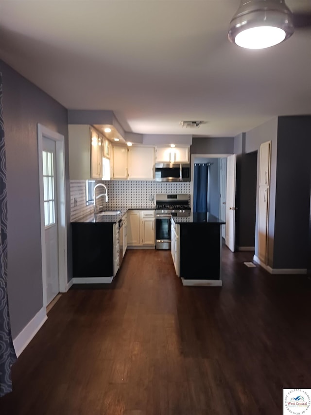501 S Oak St, Versailles, MO 65084 - kitchen featuring stainless steel appliances, dark countertops, backsplash, and dark wood-style floors