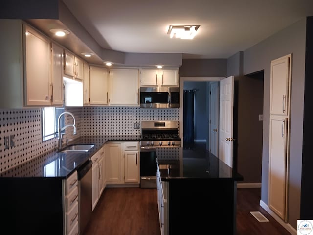 501 S Oak St, Versailles, MO 65084 - kitchen with appliances with stainless steel finishes, backsplash, a center island, dark wood-type flooring, and white cabinets