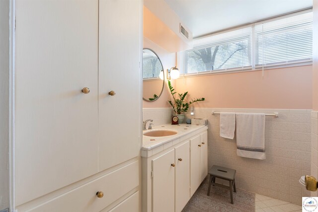 7020 Walnut Cir, Sedalia, MO 65301 - bathroom with tile patterned floors, tile walls, a wainscoted wall, vanity, and visible vents