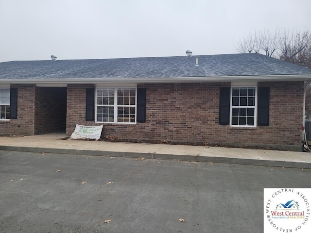 view of side of property featuring roof with shingles and brick siding