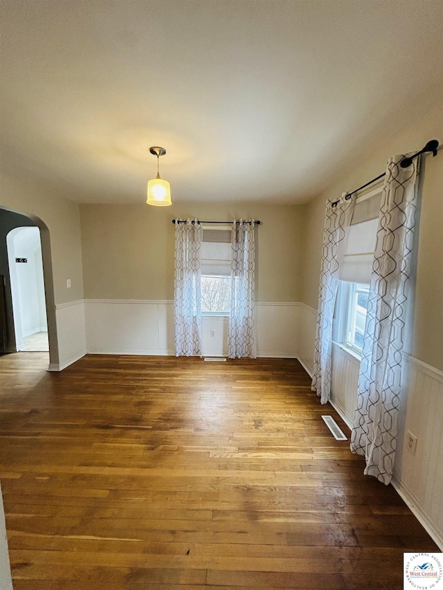 607 Laurel St, Warrensburg, MO 64093 - empty room featuring visible vents, wood finished floors, a healthy amount of sunlight, and wainscoting