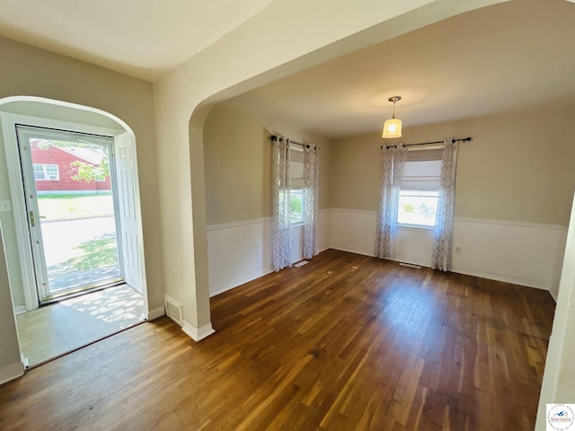 607 Laurel St, Warrensburg, MO 64093 - spare room featuring a wainscoted wall, dark wood finished floors, and arched walkways