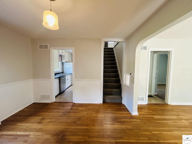 607 Laurel St, Warrensburg, MO 64093 - unfurnished living room featuring wood finished floors, stairway, and arched walkways