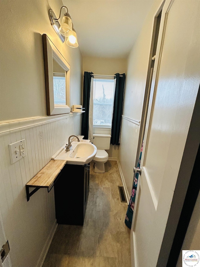 607 Laurel St, Warrensburg, MO 64093 - half bathroom featuring visible vents, toilet, vanity, and wainscoting