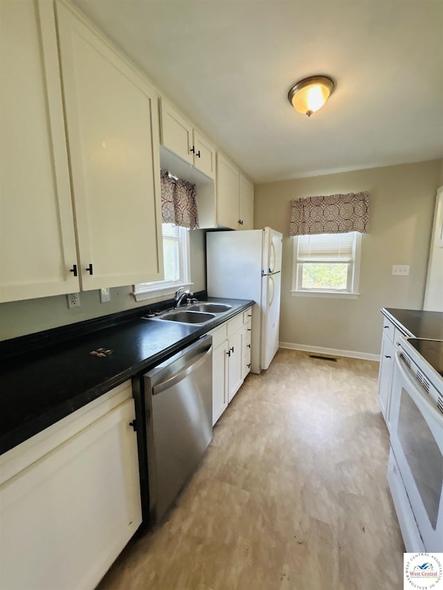 607 Laurel St, Warrensburg, MO 64093 - kitchen featuring white appliances, dark countertops, plenty of natural light, and white cabinets