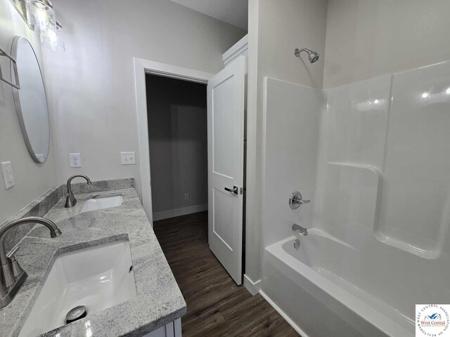 61 NW 247th Rd, Clinton, MO 64735 - bathroom featuring tub / shower combination, double vanity, a sink, and wood finished floors