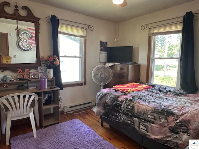 bedroom with a baseboard heating unit, wood finished floors, and a ceiling fan