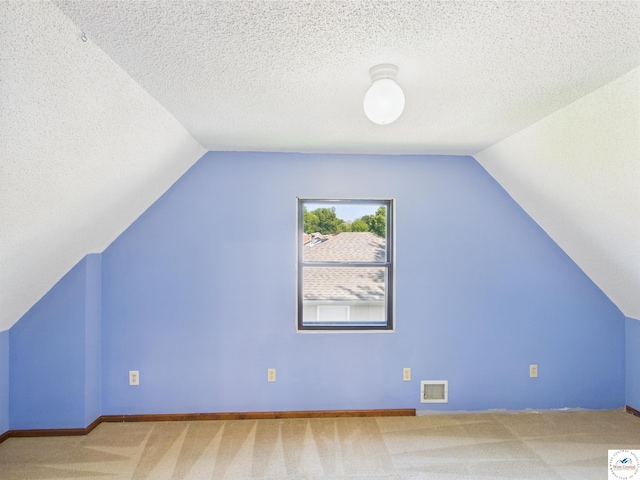 additional living space with carpet, vaulted ceiling, baseboards, and a textured ceiling
