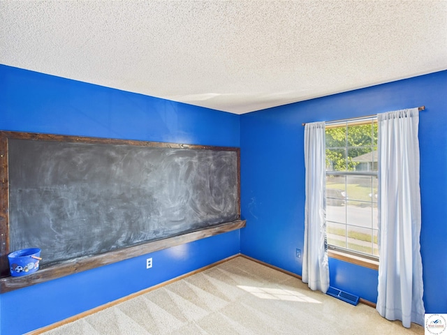 empty room featuring carpet floors, a textured ceiling, and baseboards