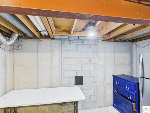 unfinished basement featuring freestanding refrigerator