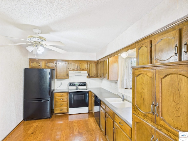 kitchen featuring black appliances, a sink, ventilation hood, brown cabinets, and a ceiling fan