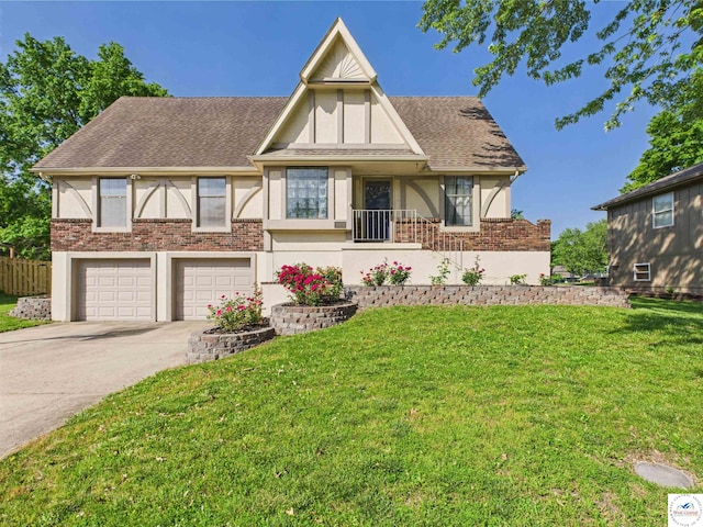tudor-style house featuring a front lawn, driveway, an attached garage, stucco siding, and brick siding
