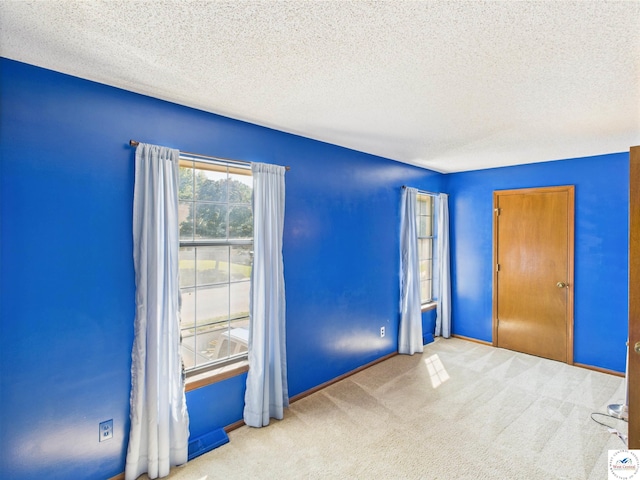 unfurnished room featuring a textured ceiling, carpet floors, and baseboards
