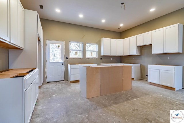 kitchen with concrete floors, a kitchen island, white cabinetry, and recessed lighting