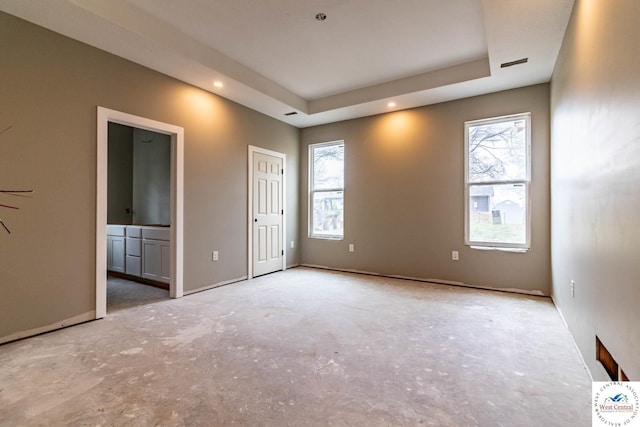unfurnished bedroom featuring ensuite bath, recessed lighting, and a raised ceiling