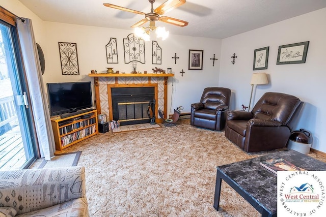 carpeted living area with a healthy amount of sunlight, a tiled fireplace, a ceiling fan, and baseboards