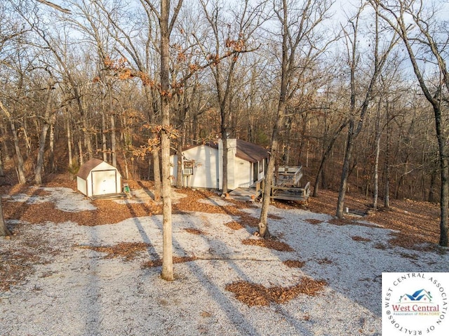 exterior space featuring an outbuilding, a shed, a detached garage, and a view of trees
