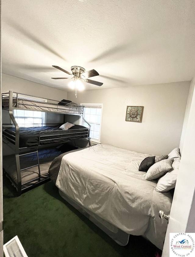 carpeted bedroom with a ceiling fan and a textured ceiling