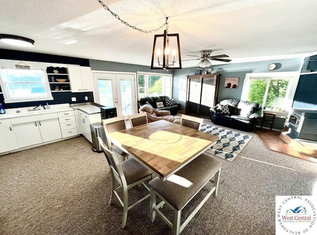 dining room featuring a ceiling fan, light carpet, a textured ceiling, and french doors