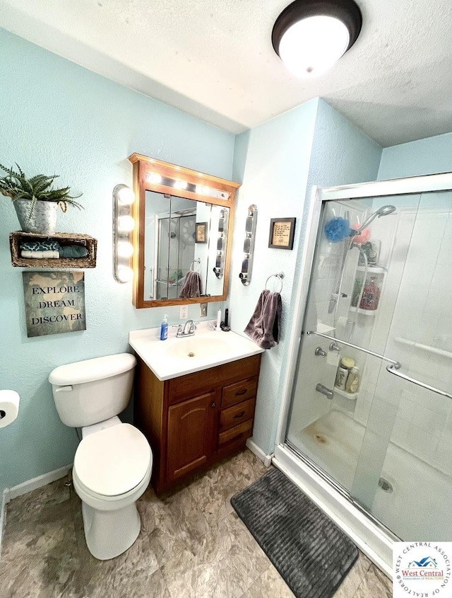 full bathroom with toilet, vanity, baseboards, a stall shower, and a textured ceiling