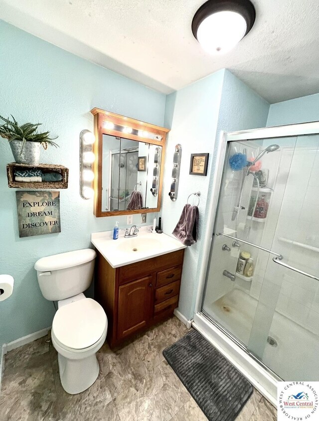 19242 Quail Rd, Warsaw, MO 65355 - full bathroom with toilet, vanity, baseboards, a stall shower, and a textured ceiling