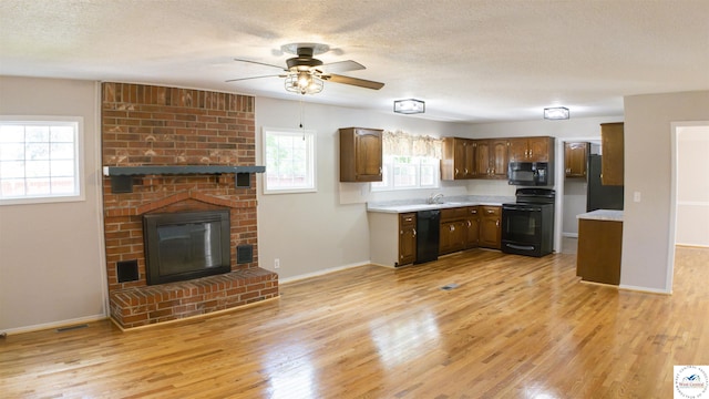 1903 E Alfresco St, Clinton, MO 64735 - kitchen featuring black appliances, light countertops, light wood-type flooring, a ceiling fan, and a fireplace