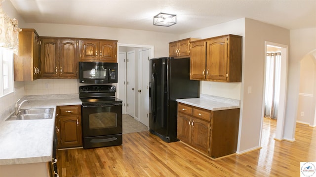 1903 E Alfresco St, Clinton, MO 64735 - kitchen featuring black appliances, light wood-style floors, light countertops, backsplash, and brown cabinetry