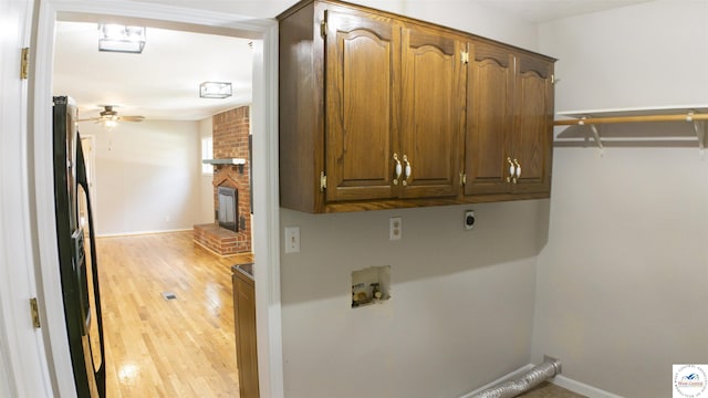 1903 E Alfresco St, Clinton, MO 64735 - laundry room with cabinet space, light wood-type flooring, ceiling fan, washer hookup, and a brick fireplace