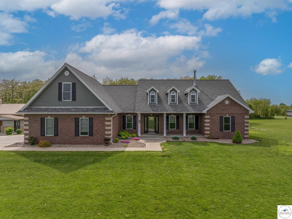3610 Cambridge Dr, Sedalia, MO 65301 - view of front of house featuring a front yard, a shingled roof, brick siding, and covered porch
