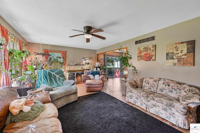 living area with wood finished floors, a ceiling fan, and a textured ceiling