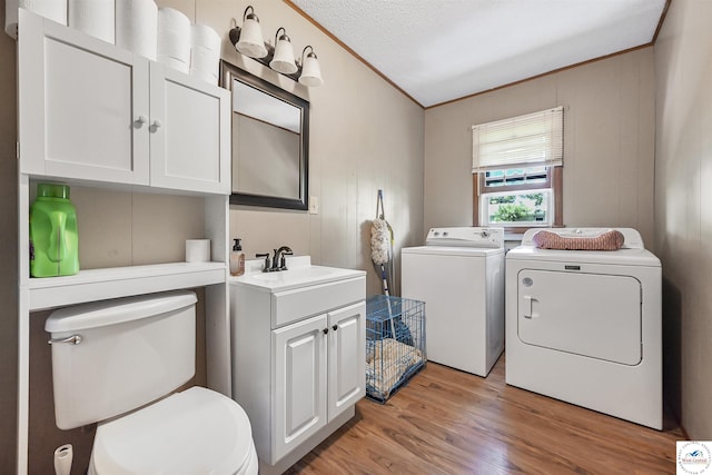washroom featuring independent washer and dryer, light wood-style floors, ornamental molding, and a textured ceiling