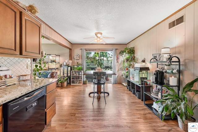 kitchen featuring black dishwasher, ceiling fan, wood finished floors, decorative backsplash, and crown molding