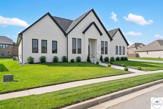 view of front of house with brick siding, central AC, and a front lawn