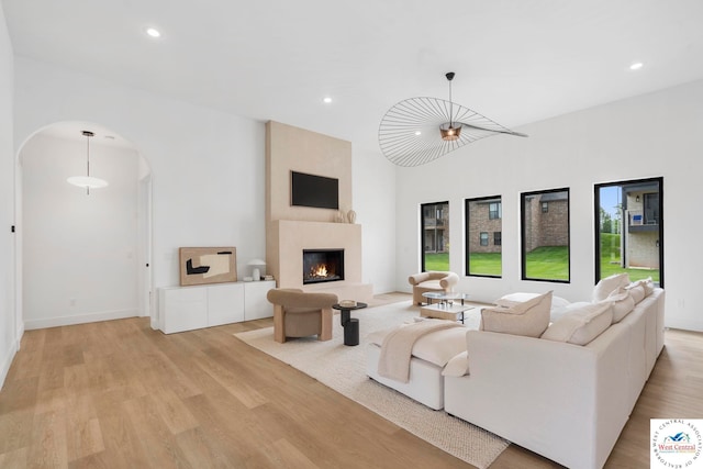 living room featuring arched walkways, light wood finished floors, recessed lighting, and a fireplace