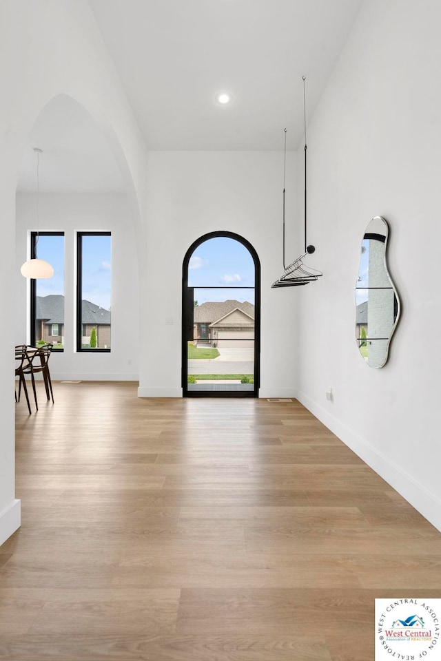 foyer entrance with light wood finished floors, baseboards, recessed lighting, and arched walkways