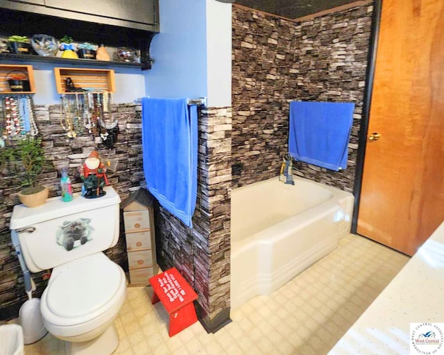 bathroom with tile patterned floors, toilet, and a tub