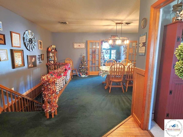 dining room with a chandelier and a wainscoted wall
