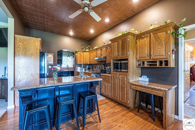1766 NW M Hwy, Clinton, MO 64735 - kitchen with appliances with stainless steel finishes, ceiling fan, light wood-style flooring, light stone counters, and a breakfast bar