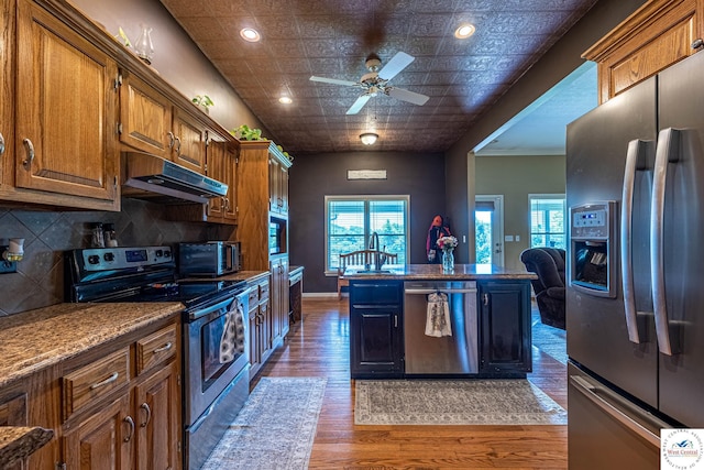 1766 NW M Hwy, Clinton, MO 64735 - kitchen featuring stainless steel appliances, under cabinet range hood, wood finished floors, a ceiling fan, and backsplash