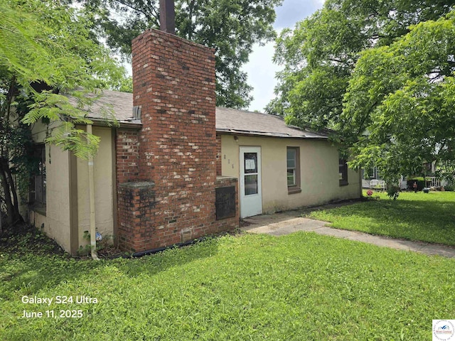 107 W 6th St, Urich, MO 64788 - rear view of property with a lawn, a chimney, a shingled roof, and stucco siding