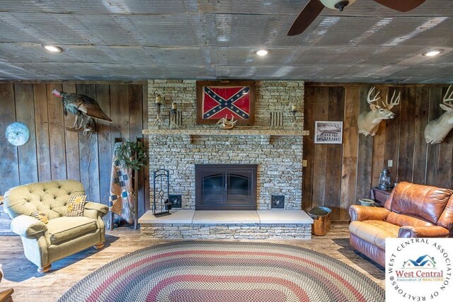662 W 6th St, Schell City, MO 64783 - living room with wooden walls, a ceiling fan, wood finished floors, and a fireplace