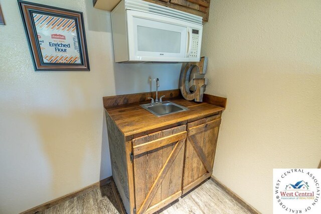 662 W 6th St, Schell City, MO 64783 - indoor wet bar featuring white microwave, baseboards, and light wood-style floors