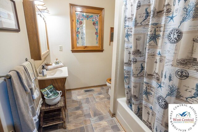 662 W 6th St, Schell City, MO 64783 - full bath with vanity, baseboards, stone finish floors, shower / bath combo with shower curtain, and toilet
