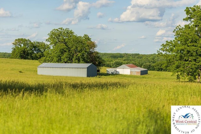 662 W 6th St, Schell City, MO 64783 - view of yard featuring an outbuilding, an outdoor structure, and a wooded view